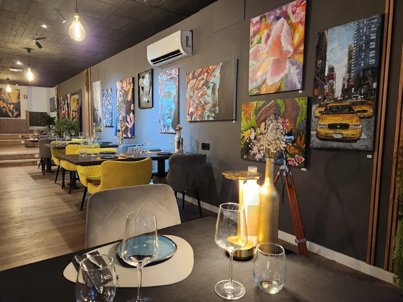 The main dining room at The Boab Tree, one wall hung with original paintings above ochre velvet chairs